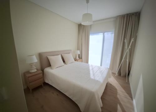 a bedroom with a white bed and a large window at Garden House 2 in São Vicente Ferreira