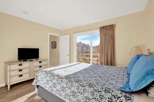 a bedroom with a bed and a tv and a window at Lighthouse Point Rental 8B in Tybee Island