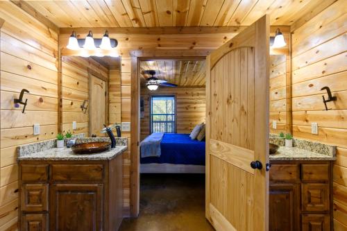 a log cabin bathroom with two sinks and a bed at Wide Glide Lodge - In-home Movie Room, Hot Tub and Large 1-acre property with Playset in Broken Bow