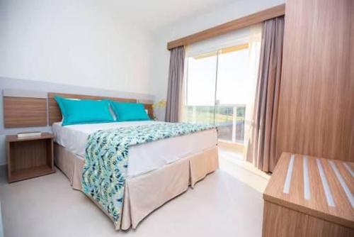 a bedroom with a bed with blue pillows and a window at Ilhas do Lago in Caldas Novas