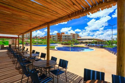 a deck with tables and chairs next to a pool at Ilhas do Lago in Caldas Novas