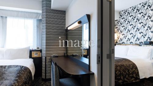 a hotel room with a desk and two beds at APA Hotel Kyoto Ekimae in Kyoto