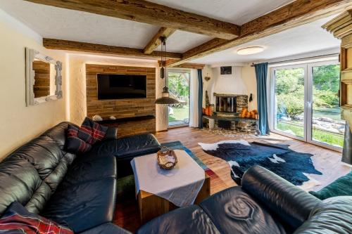 a living room with a leather couch and a fireplace at Smileys Kinderhotel in Trebesing