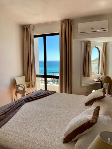 a bedroom with a bed with a view of the ocean at Salema Beach Hotel in Salema