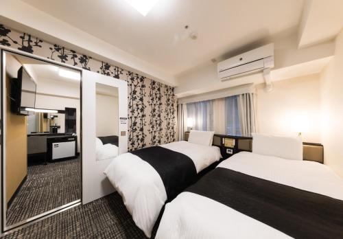 a hotel room with two beds and a mirror at APA Hotel Kyoto Ekimae in Kyoto