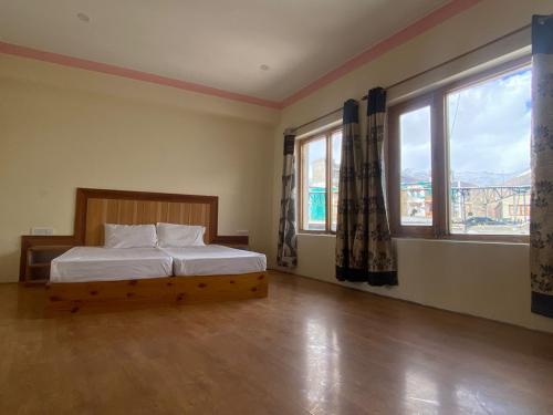 a bedroom with a bed and two windows at Summer Villa in Leh