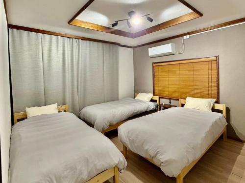 a room with two beds and a ceiling at Iwaki yamakage no Yado-いわき山影の宿- in Iwaki
