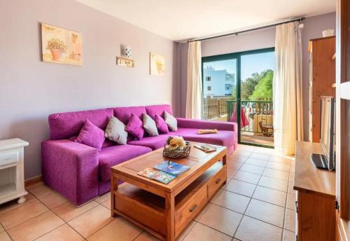 a purple couch in a living room with a table at Apartamento Ca Na Fina, tranquilo y cerca de la playa de Es Pujols in Es Pujols