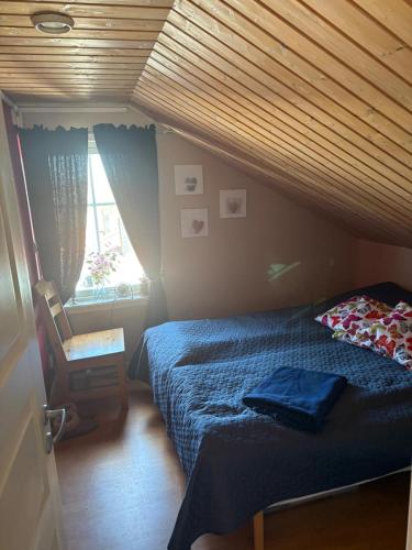a bedroom with a bed and a chair and a window at Villa i sommaridyll 4 sovrum in Strömstad