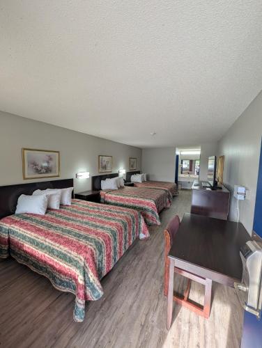 a hotel room with three beds and a table at Garden Inn Adairsville in Adairsville