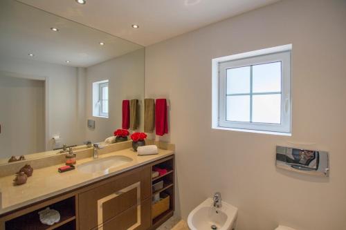 a bathroom with a sink and a toilet at Villa Buganvilia III in Aroeira