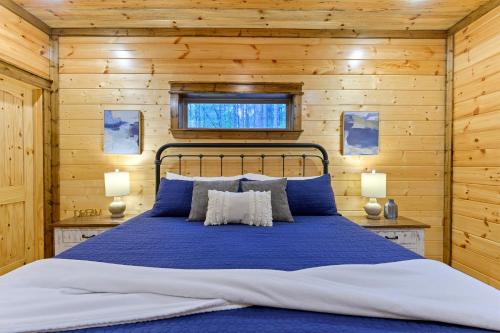 a bedroom with a blue bed in a wooden wall at Low Rider Lodge - Backs to Pine Forest and ATV Trail Access from Driveway in Broken Bow