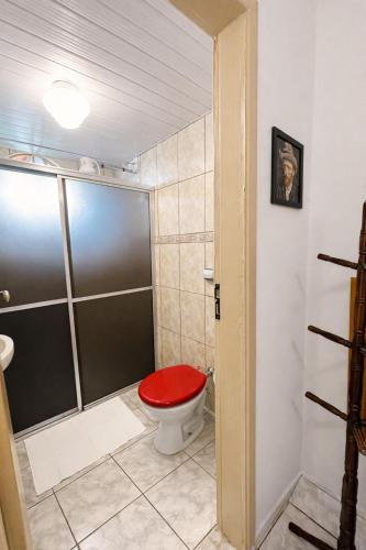 a bathroom with a toilet with a red seat at Vila Rica Hospedaria in Ouro Preto