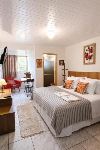 a bedroom with a large bed and a living room at Vila Rica Hospedaria in Ouro Preto