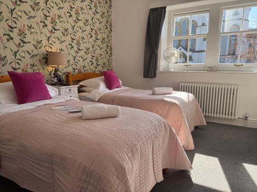 a bedroom with two beds with pink sheets and a window at The Nags Head - Room only accommodation in Lyme Regis