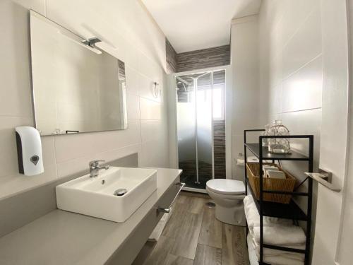 a white bathroom with a sink and a toilet at Apartamento A pie de Playa in Miño
