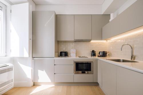 a kitchen with white cabinets and a sink at Ando Living - Abrantes 10 House in Lisbon