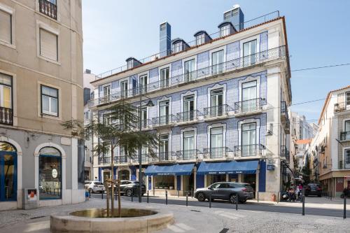 a building on a street with a palm tree in front at Ando Living - Abrantes 10 House in Lisbon