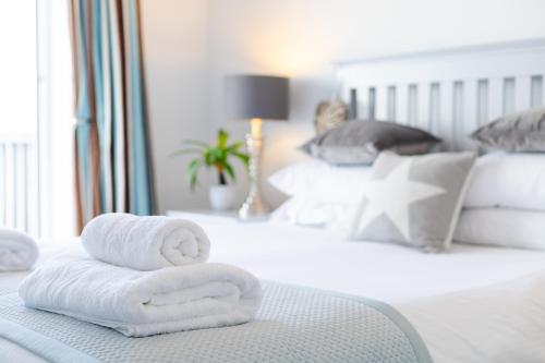 a pile of towels sitting on top of a bed at West Bay Cottages Yarmouth Isle of Wight in Yarmouth
