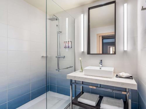ein Badezimmer mit Waschbecken und Dusche in der Unterkunft Movenpick Hotel Abidjan in Abidjan