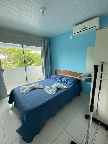 a blue bedroom with a bed with two towels on it at Pousada Baia dos Golfinhos in Governador Celso Ramos