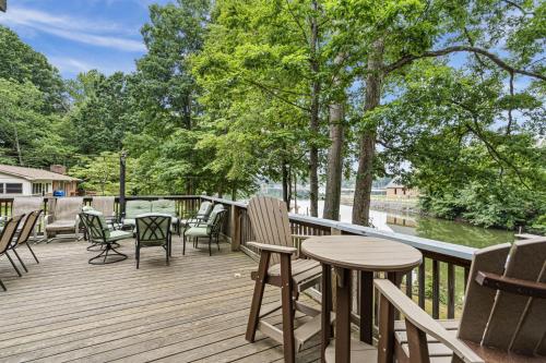 a wooden deck with chairs and tables and trees at Pool Table, Massive Balcony, Firepit, & Spacious! in Sherrills Ford