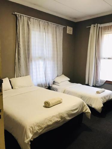 two beds in a room with white sheets at Corfield in Durban