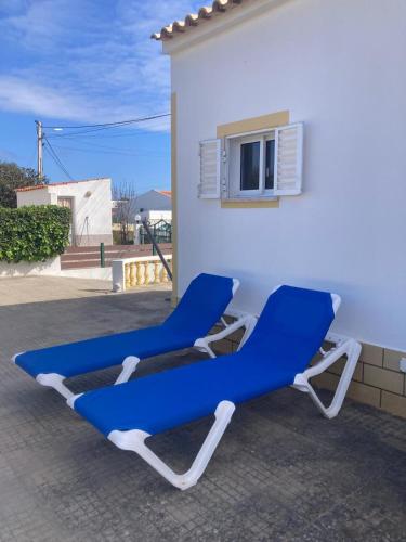 two blue and white lounge chairs in front of a building at Spacious House in Sagres with Private Patio & BBQ in Sagres
