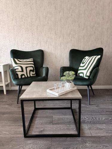 two chairs and a coffee table in a living room at Ventos g 51 Apartment in Mažeikiai