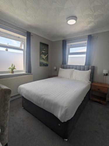 a bedroom with a large bed and two windows at The Claremont Preston in Preston