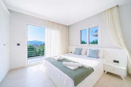 a white bedroom with a bed and a large window at Villa Riva in Oludeniz