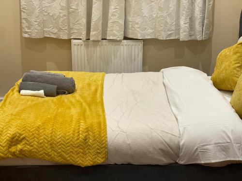 a bed with a yellow and white blanket on it at Standish Haven Ensuite Room in Standish