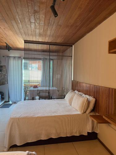 a bedroom with a large bed with a large window at Pituba Vile - Apartamento Mandala in Itacaré