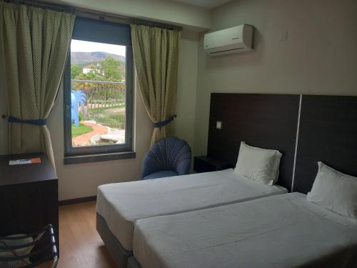 a hotel room with two beds and a window at Hotel Lagar do Lago in Castanheira de Pêra