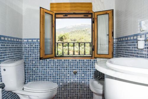 baño con aseo y lavabo y ventana en Casa Felix, en Segura de la Sierra