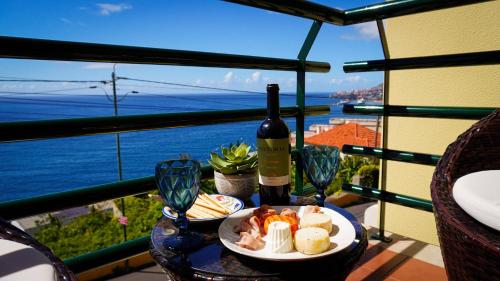 a table with a plate of food and a bottle of wine at Villa Frente Mar by ESCAPE to Madeira in Funchal