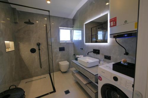 a bathroom with a shower and a sink and a washing machine at Aithra Suite - Europa Hotel in Korinos
