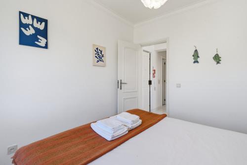 a white bedroom with a bed with towels on it at BC Beach House - Santa Cruz in Santa Cruz