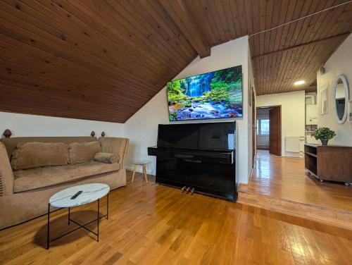 a living room with a couch and a flat screen tv at Spacious Condo w Terrace & Piano in Sesvete