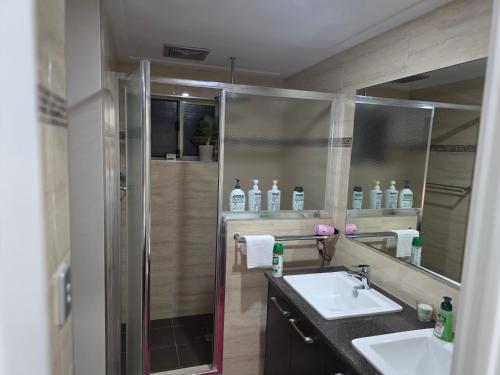 a bathroom with a shower and two sinks and a mirror at Sunset Beach B&B in Waggrakine