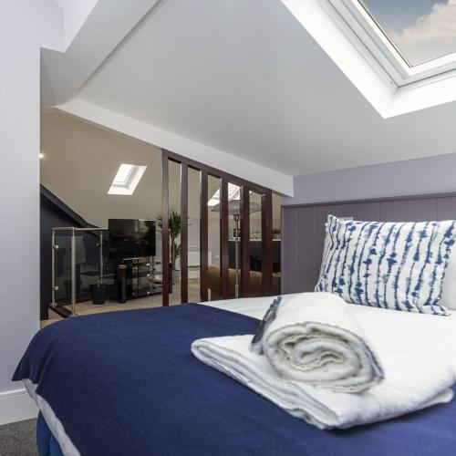 a bedroom with a bed with a blue blanket and a pillow at Luxury modern Loft apartment by Bootique in Wakefield