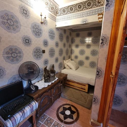 a small room with a bed and a desk with a laptop at Momo's villa in Aït Ourir