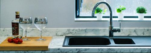 two wine glasses on a cutting board next to a kitchen sink at BOOTique House - Luxury Group Accommodation for 12 in Wakefield