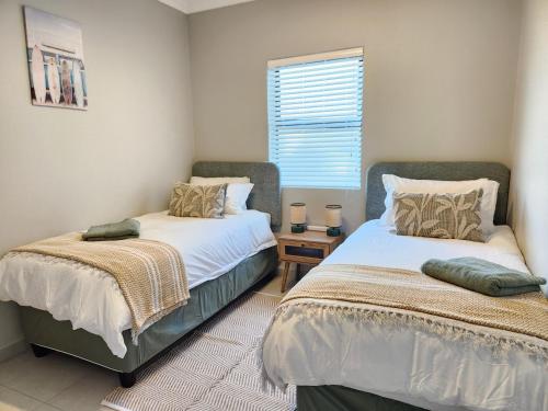 a bedroom with two beds and a window at Beach Haus Unit 1 in Cape Town