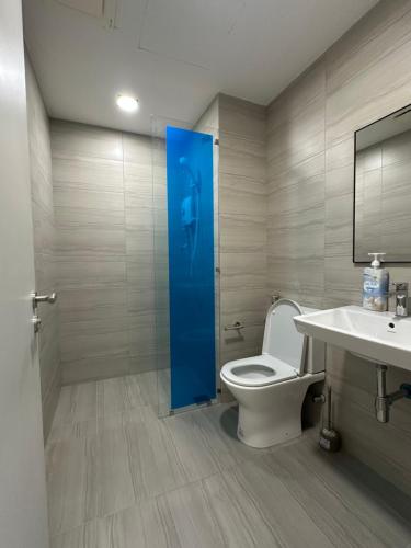 a bathroom with a toilet and a blue door at QH Guesthouse in Shah Alam