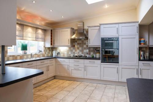 a kitchen with white cabinets and a stove top oven at Stylish family home in desirable Penylan + Parking in Cardiff