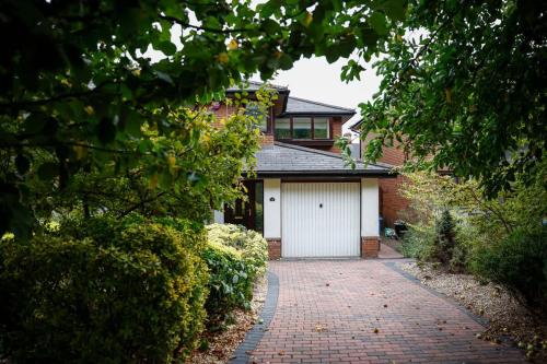 a brick house with a white garage and a driveway at Stylish family home in desirable Penylan + Parking in Cardiff