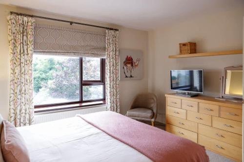 a bedroom with a bed and a tv and a window at Stylish family home in desirable Penylan + Parking in Cardiff