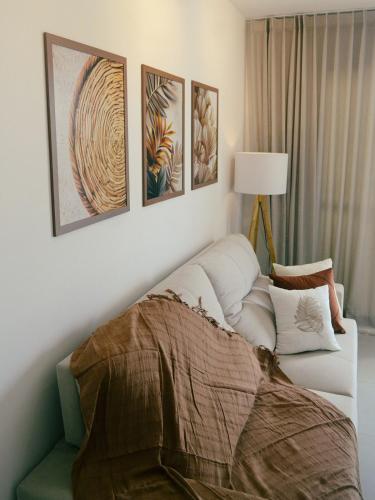 a living room with a white couch and four paintings at Airport subway apartment in Lauro de Freitas