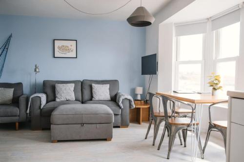 a living room with a couch and a table at Barry Island Beachfront Apartment - Stunning Bay Views and Private Parking in Barry